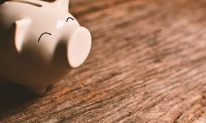 Happy expressive piggy bank on wooden plank