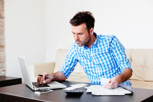 young man paying bills and budgeting young man paying bills at desk