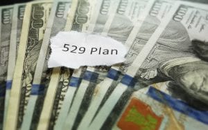 529 Plan written on ripped paper on top of stack of 100 U.S dollar bills