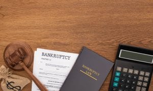 top view of calculator, bankruptcy law book, documents, money bag and gavel on wooden background