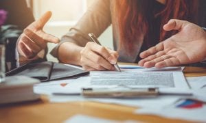 Two people co-signing a loan while lender gives them information