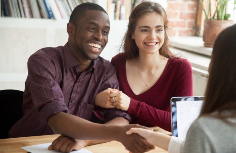 Couple shaking hands with businesswoman making deal