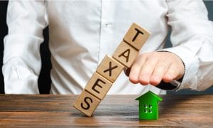 Man protects model house from falling tax blocks with hand