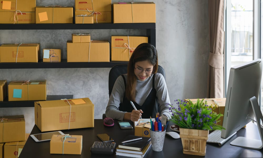Businesswoman working from her own homemade business signing shipping labels