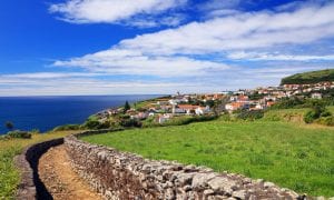 Photo of Flores Island, Azores with cobblestone short wall path and green open field with town in view