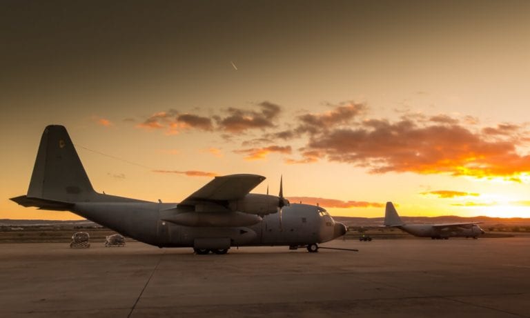 Military aircraft wating to take off on runway during sunset