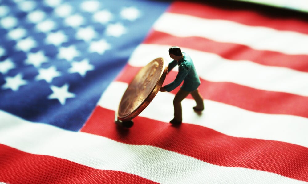 Small military figure on American flag lifting up coin