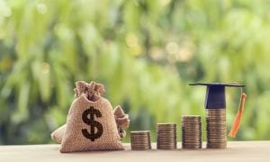 Moneybags and stacks of coins with graduation cap on top