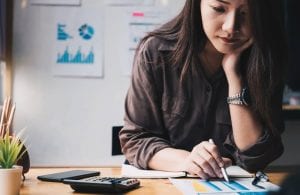 Business woman using calculator for do math for finances on wooden desk