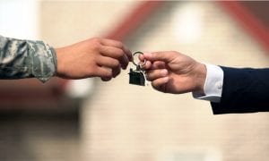 Man in military uniform receiving house key from realtor