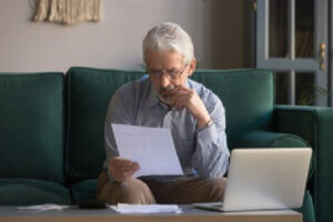 Retired man paying off his credit card bills on his laptop