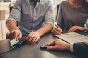 Couple at a car dealership paying for new car with credit card