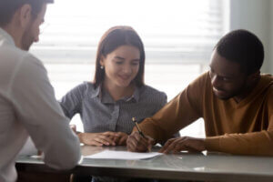 Young couple signing the paperwork to borrow money from a lender