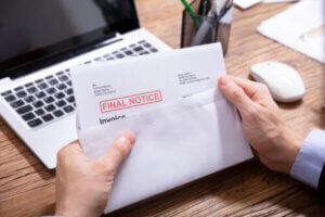 Man at desk opening a bill that says final notice for debt