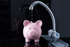 Water from sink dripping into piggy bank