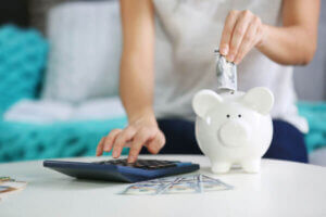 Woman saving money from her paycheck and putting it into a piggy bank