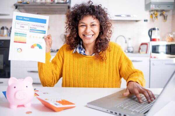 Mujer feliz comprobando su buena puntuación de crédito en línea.