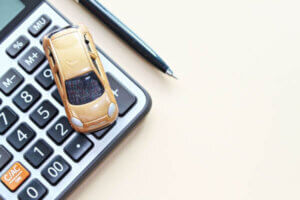 Top view or flat lay of miniature car model, calculator and pen on office desk table representing a car loan.