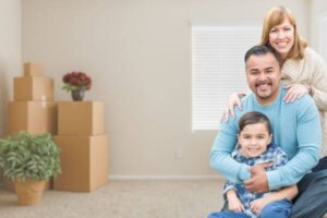 Familia feliz con hijo en habitación con cajas de mudanza empaquetadas.