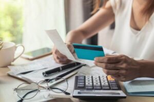 Young woman sitting at a desk, reviewing her bank account and considering closing it.