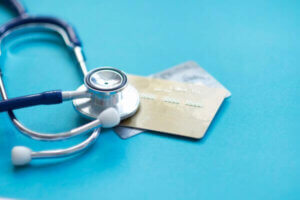 Stethoscope on mock up Credit Card in hospital desk representing medical debt.