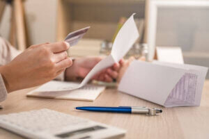 Hand with credit card and paper on desk representing checking credit report.