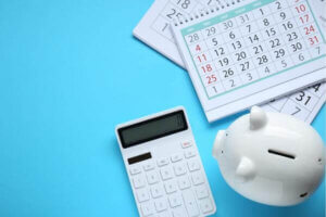 Piggy bank and calculator on light blue background representing personal loan terms